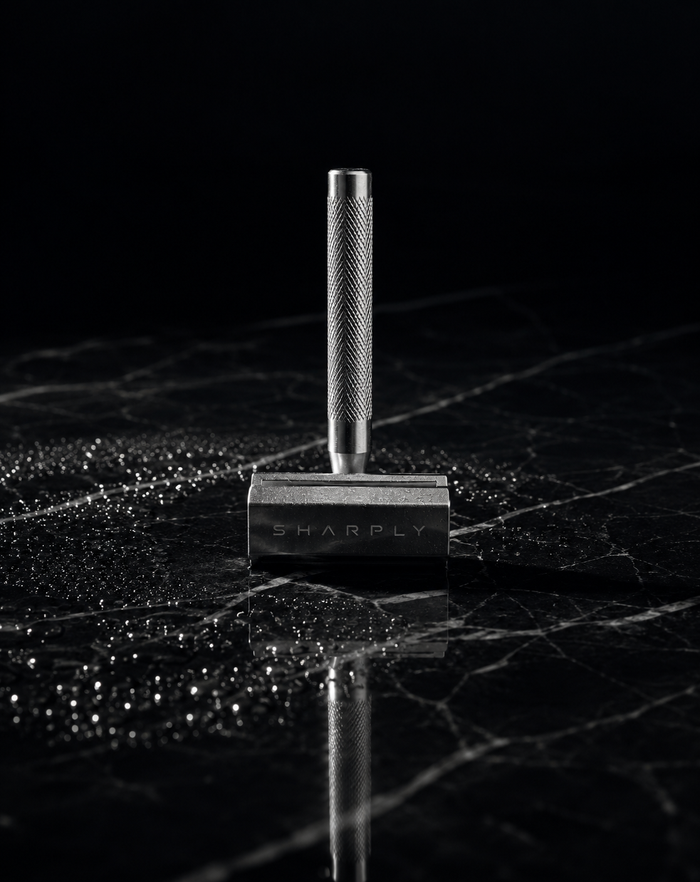 Sharply Blade One standing upright on wet black marble, the SHARPLY wordmark engraved on the stainless steel head